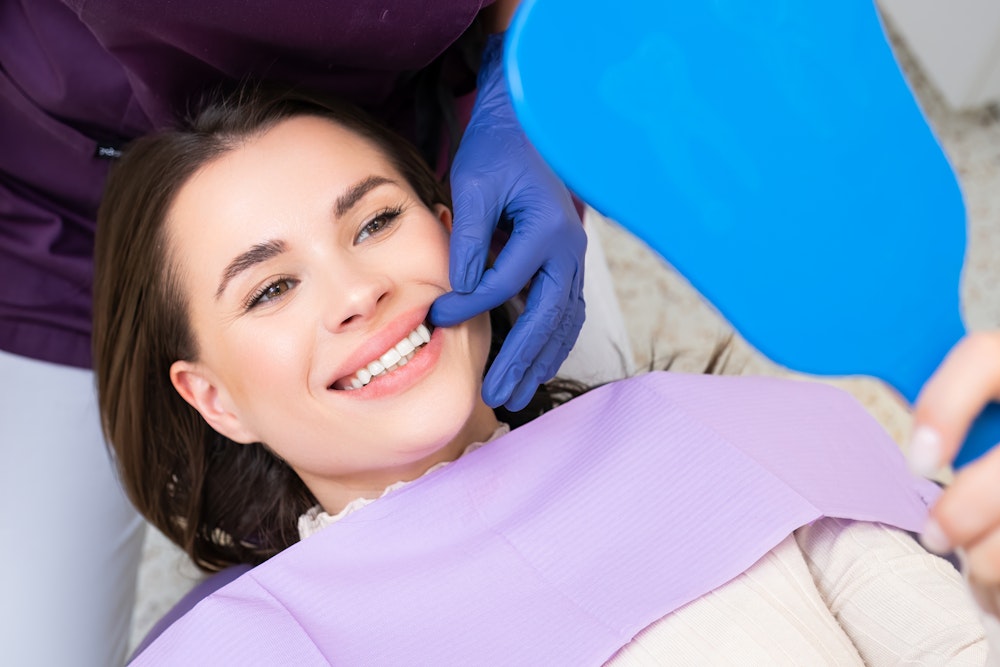 Woman smiling in the mirror at the dentist