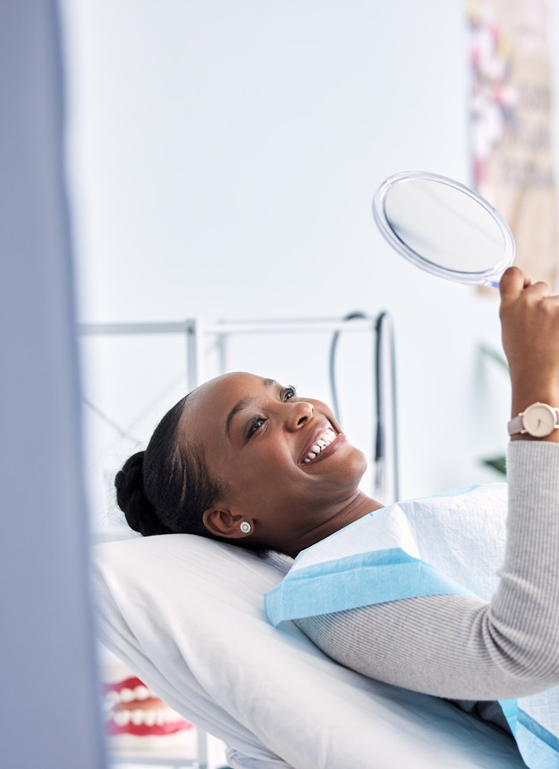 woman examining her smile in the mirror