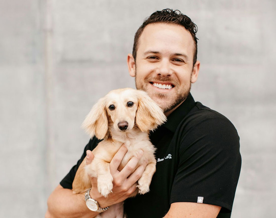 Dr. John-Morgan Correll smiling and holding Lemon, the Dental Haus office dog