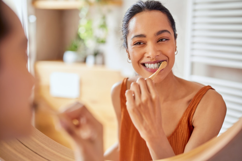 Woman smiling and brushing her teeth