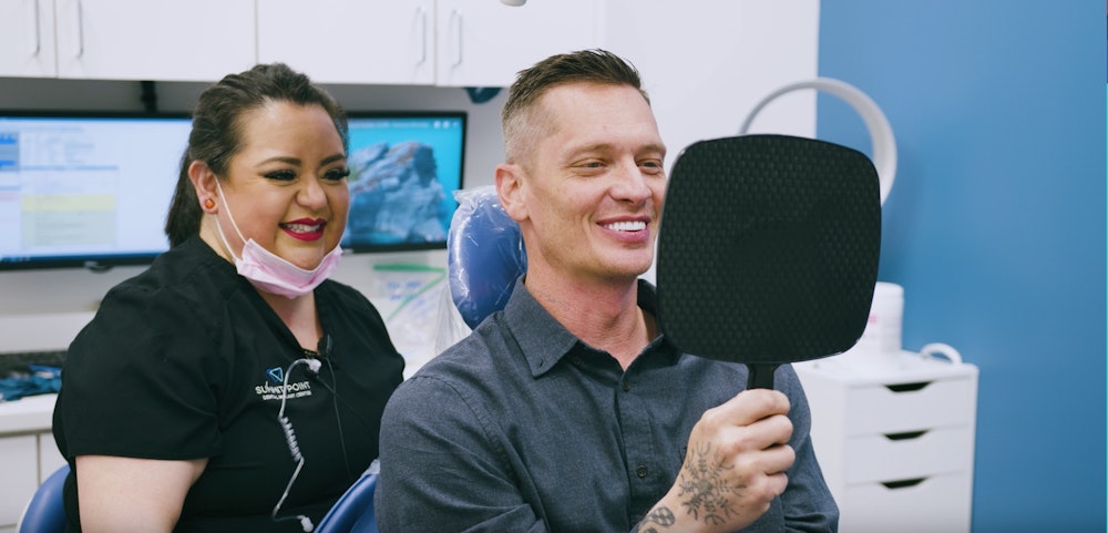 dental patient smiling in a handheld mirror
