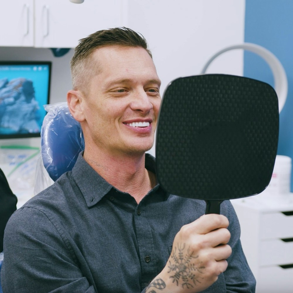 dental patient smiling in a handheld mirror