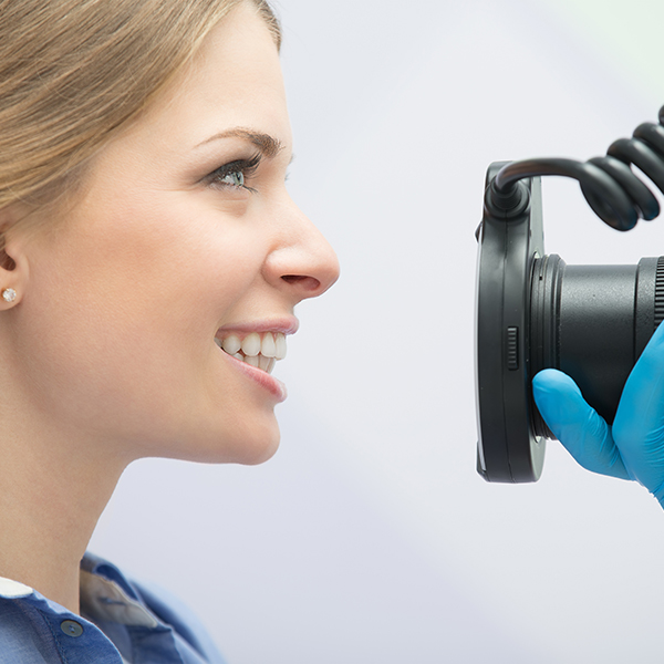 Young woman getting her jaw photographed by a medical professional