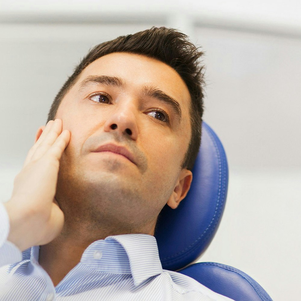 Man holding jaw with pained expression