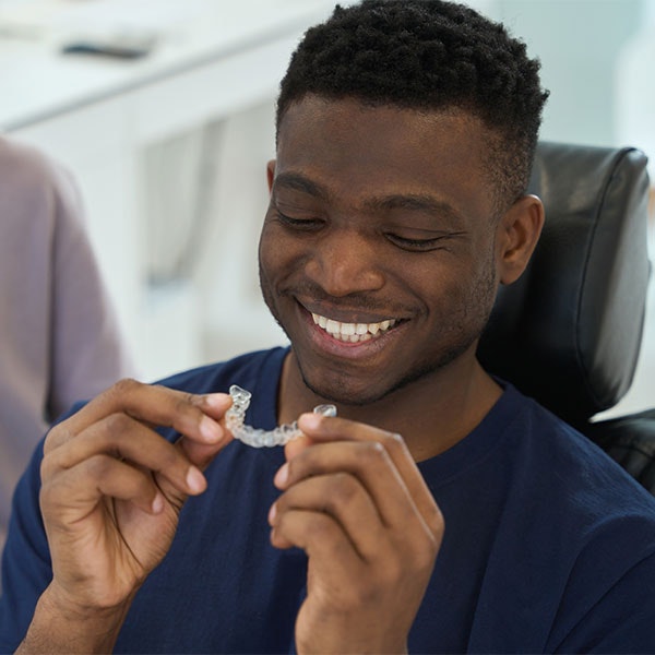Man at the dentist looking at a clear aligner
