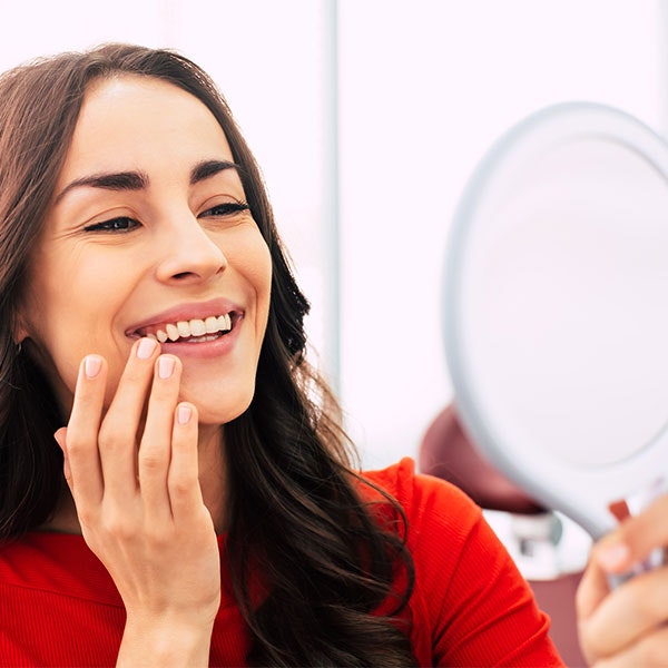 Woman smiling in a mirror at the dentist