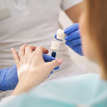 Dentist showing patient model of a dental crown