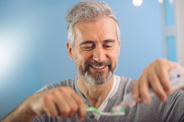Man putting on toothpaste on toothbrush