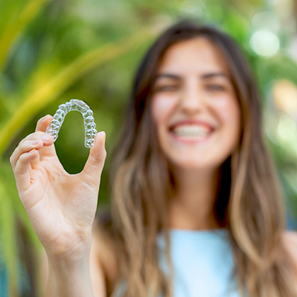 Laughing woman holding a clear aligner