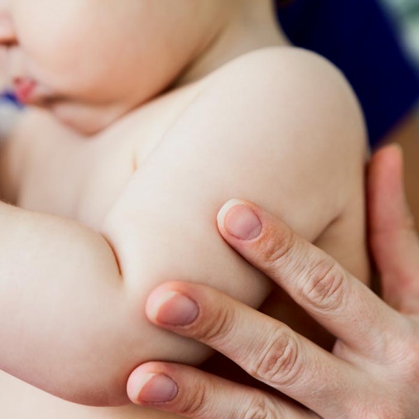 mother touching baby's shoulder