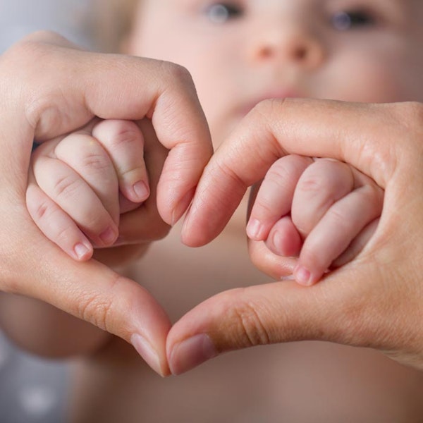 child and mother making heart shape with their hands