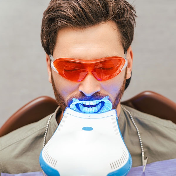 Young bearded man getting his teeth whitened in a dental office