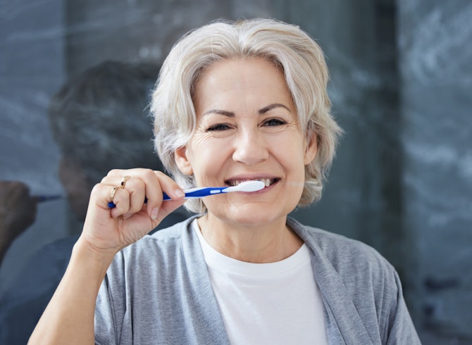 mature woman brushing teeth