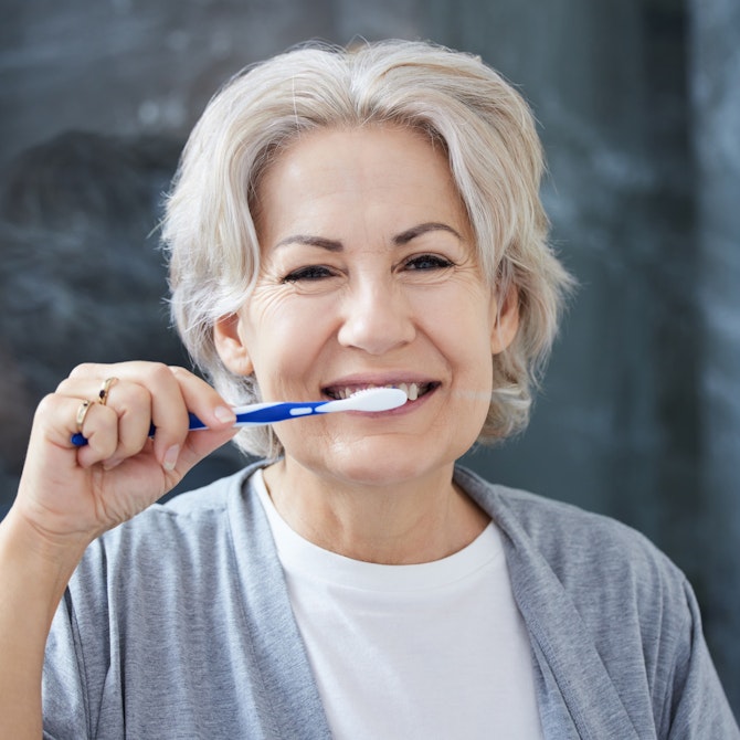 mature woman brushing teeth