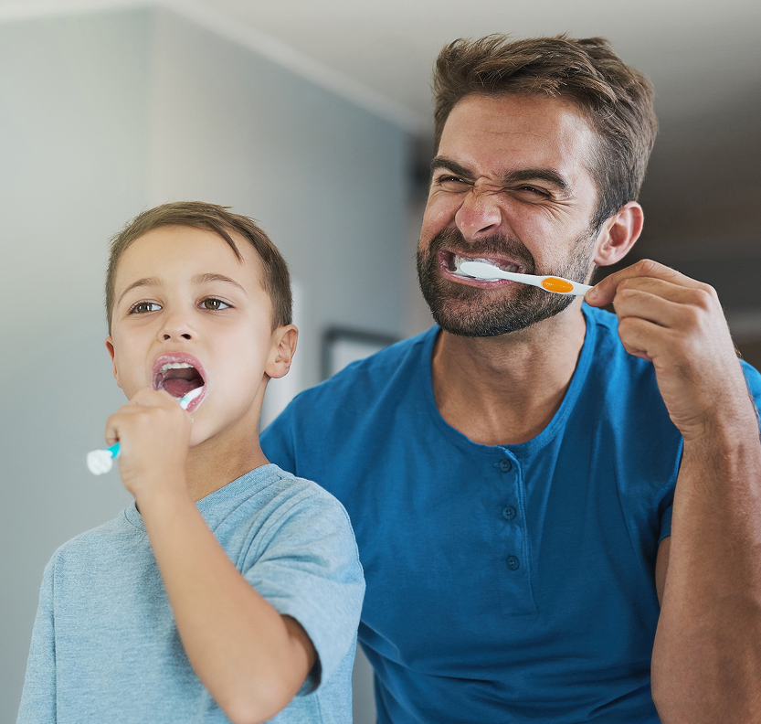 Dad and young girl brushing teeth together