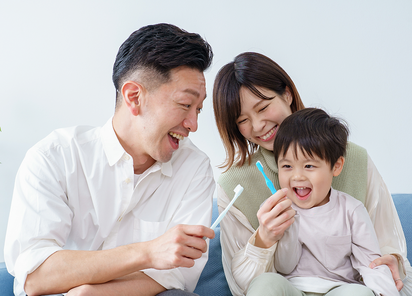 Parents brushing teeth with a smiling baby