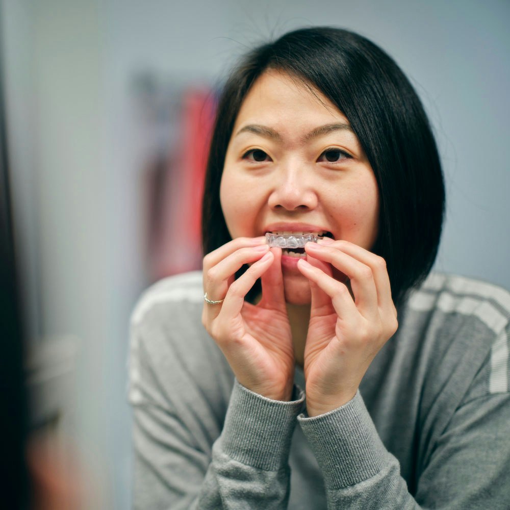 Smiling teen girl putting in Invisalign aligner