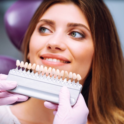Dentist color-matching veneers to a patient's smile