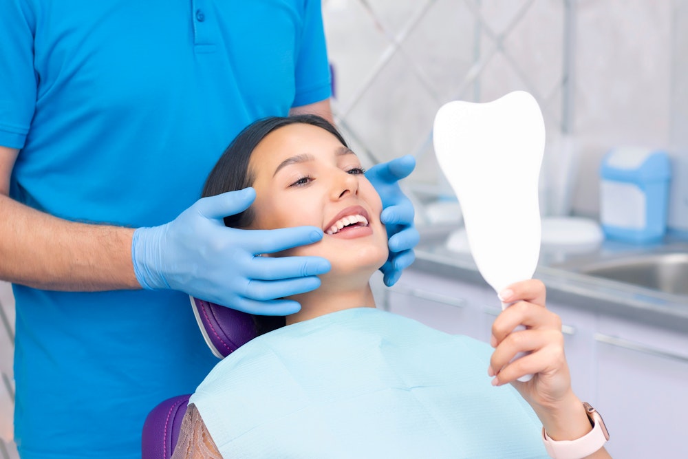 Young woman smiling in mirror at dentist
