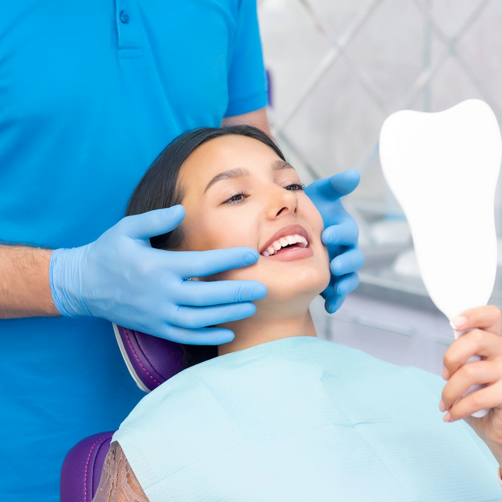 Young woman smiling in mirror at dentist