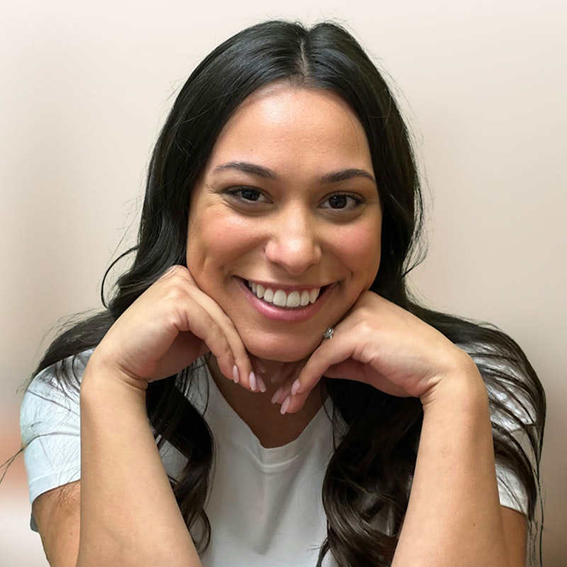 Young woman smiling with hands gently under her chin, highlighting her bright, natural-looking smile