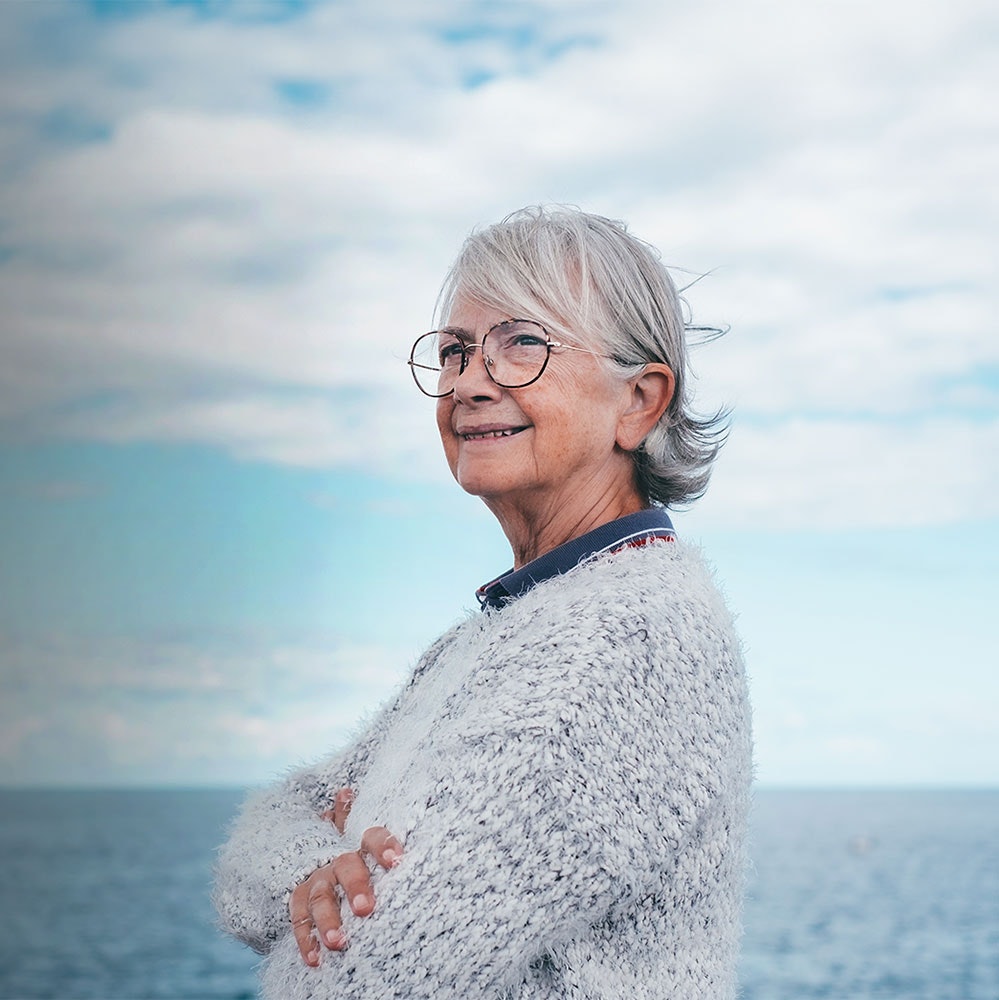 Elderly woman with well-managed diabetic retinopathy looking at the ocean
