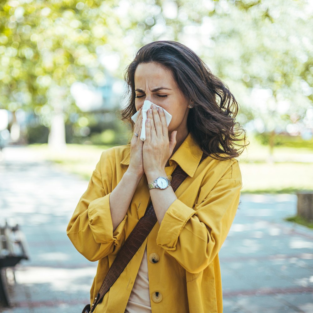 Woman outdoors sneezing