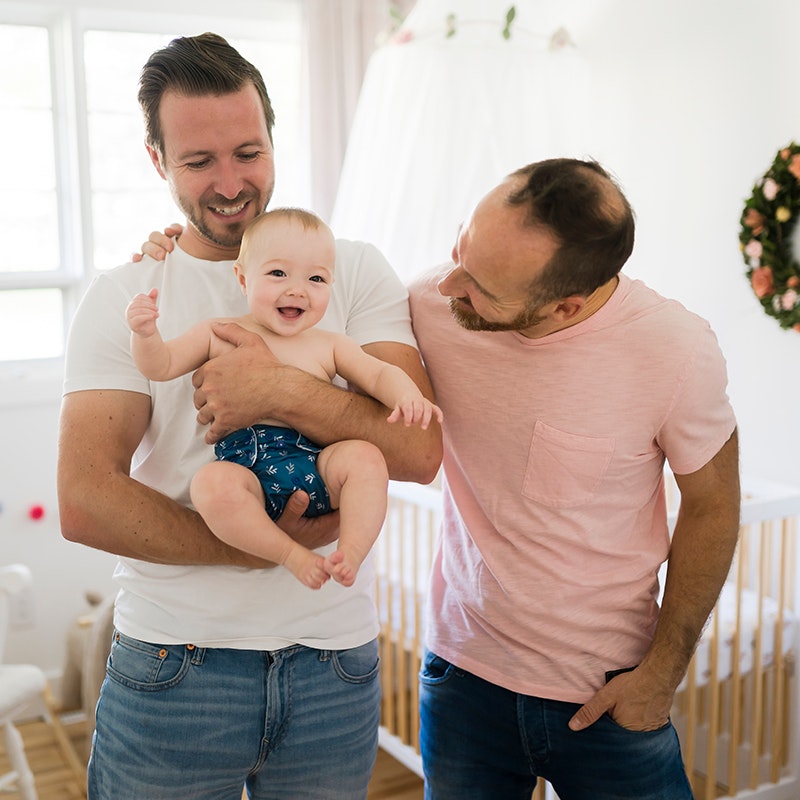 male same sex couple holding a happy baby