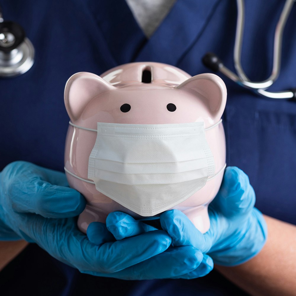 a medical worker holding a piggy bank