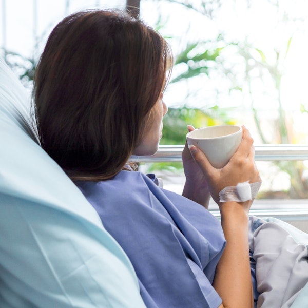 Young woman drinking tea in a hospital bed