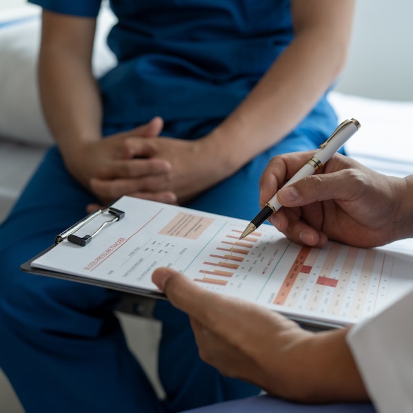 Man sitting on doctor's table while the doctor takes notes