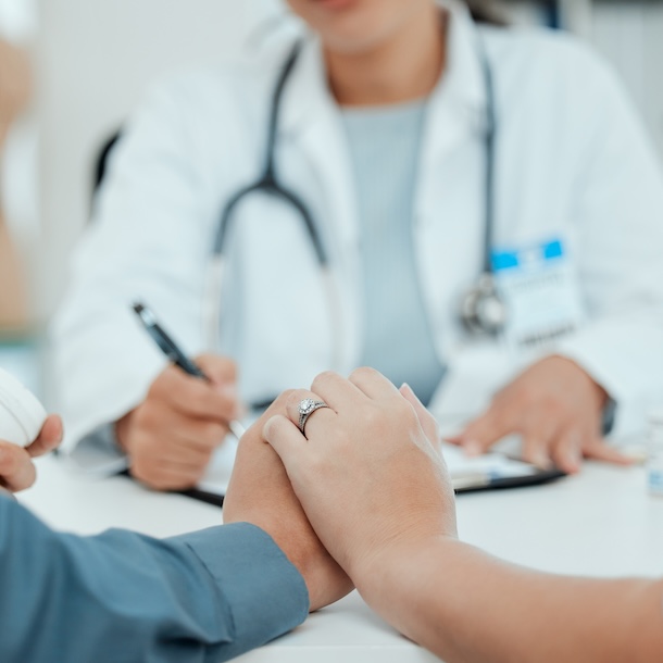 couple holding hands in front of doctor