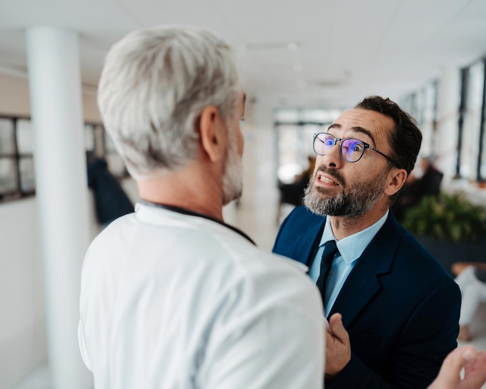 Man threatening another man in a white coat