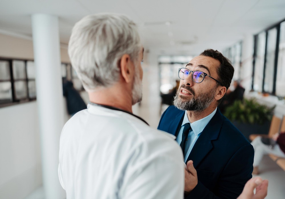 Man threatening another man in a white coat