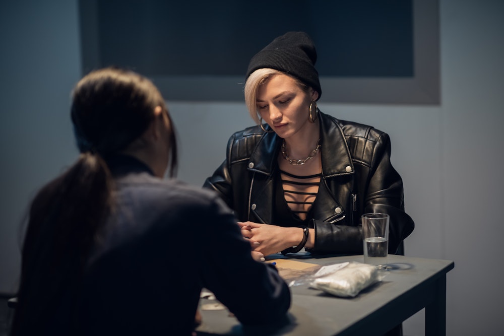 Young woman being interrogated by an officer at the police station
