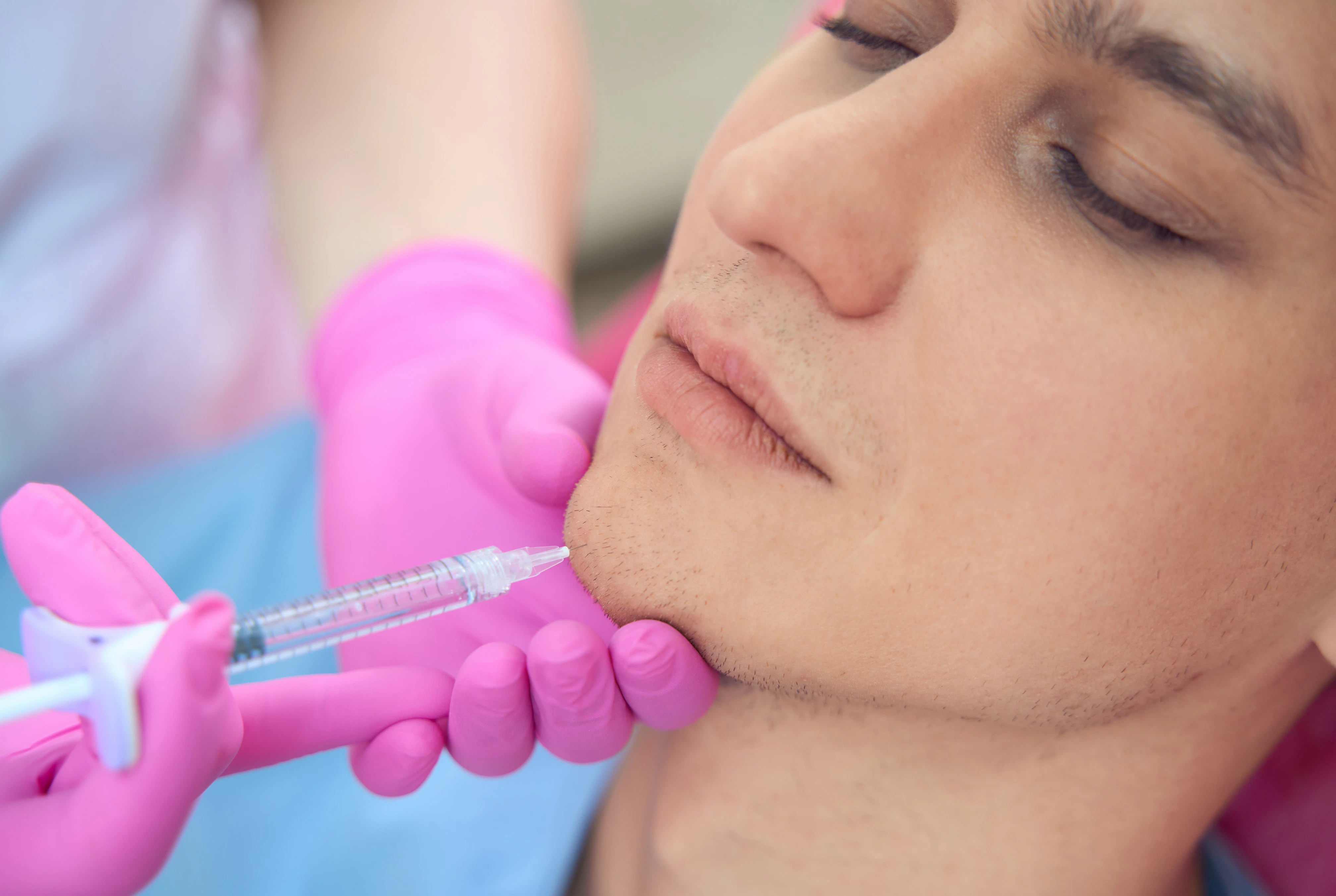 man getting dermal filler injection in his chin