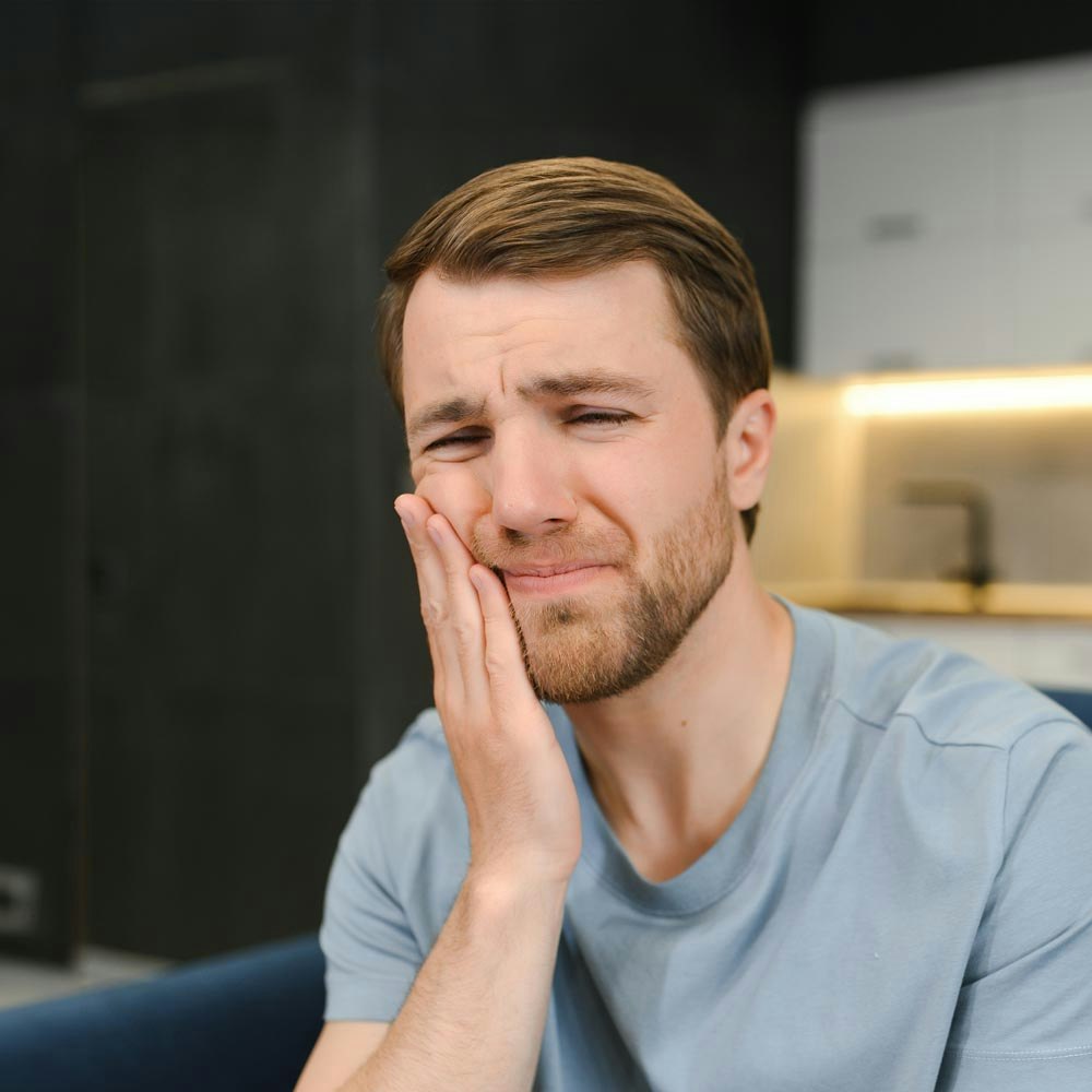 Man holding cheek in pain