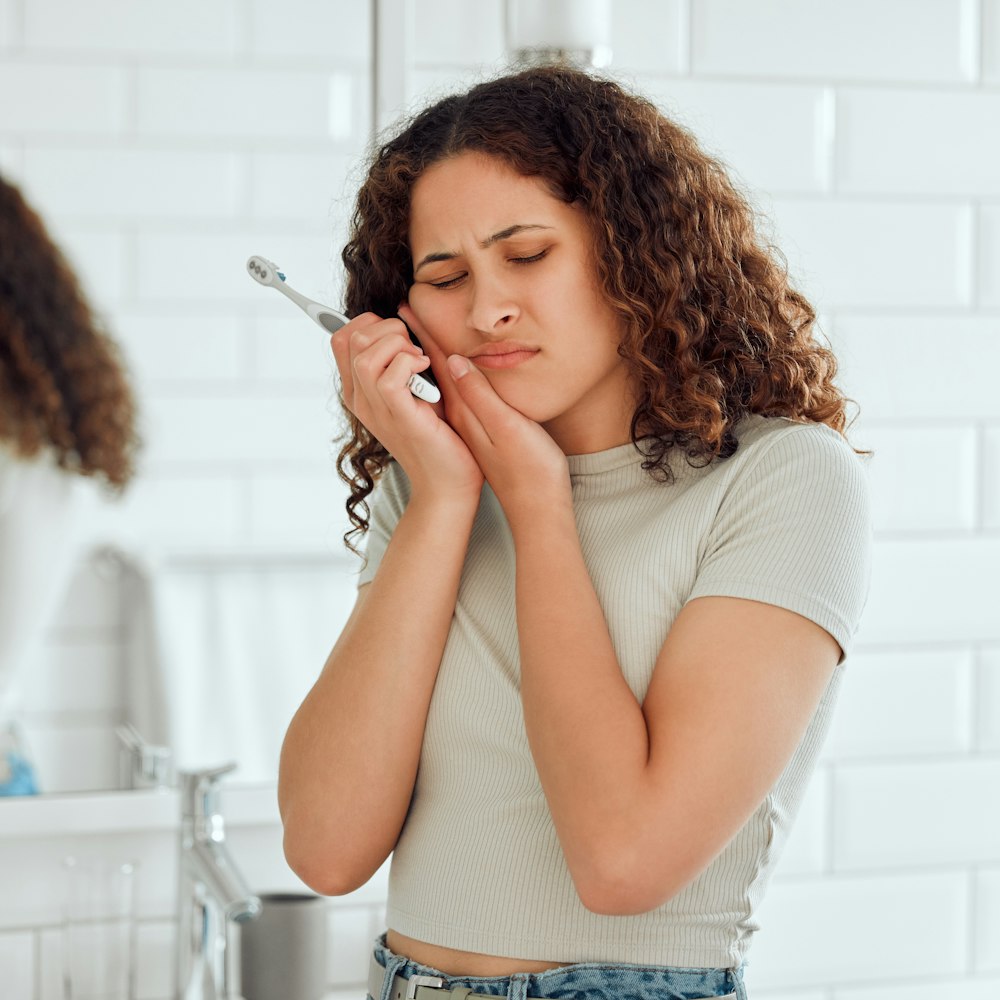 Woman in dental pain while brushing her teeth