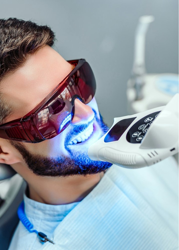 Smiling man getting teeth whitened
