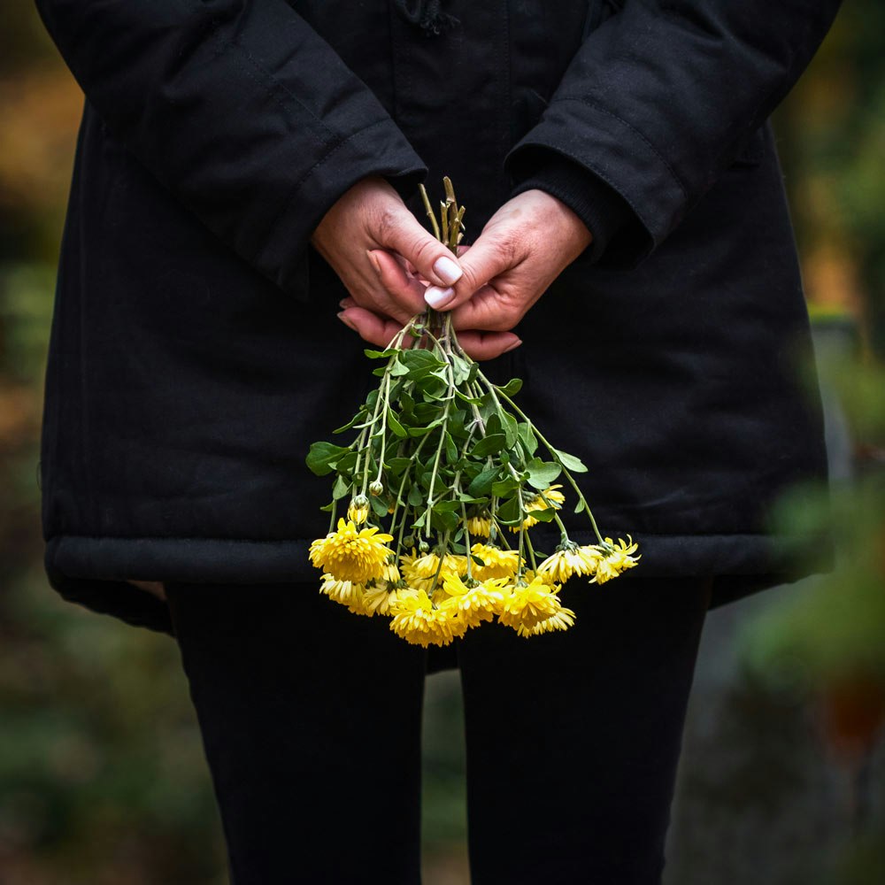 Person holding yellow flowers