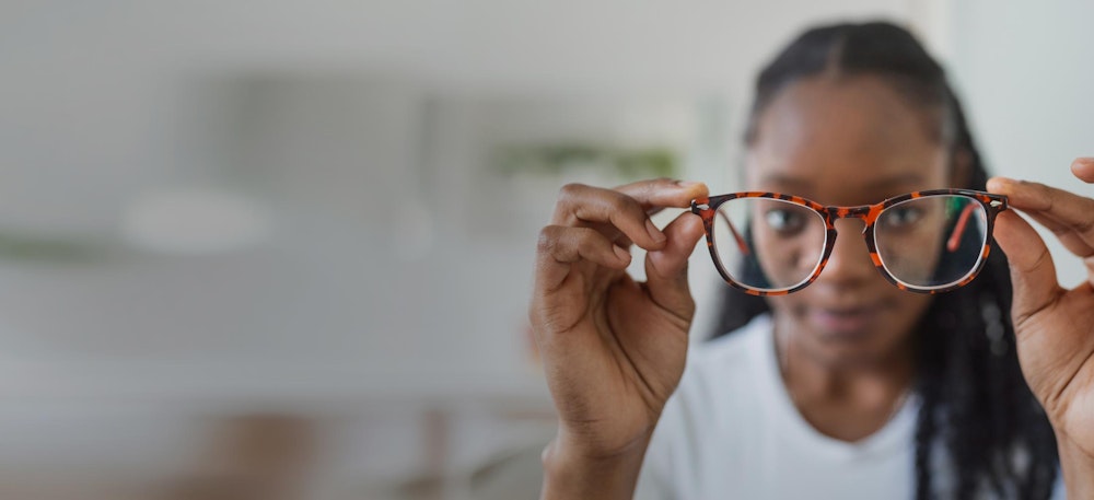 Woman holding glasses in front of her face