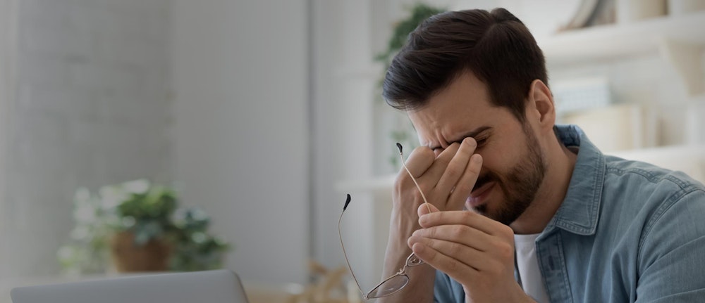 Man rubbing painful eyes