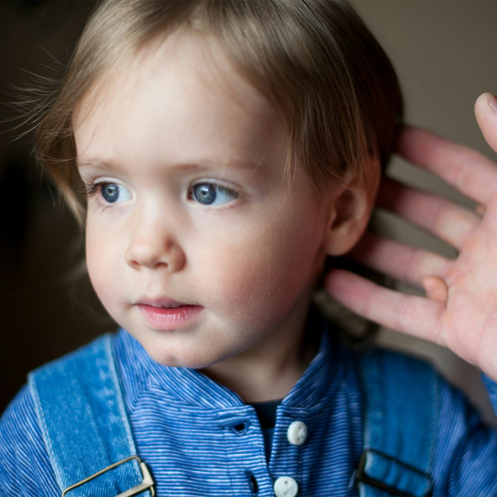 Child with adult examining ear