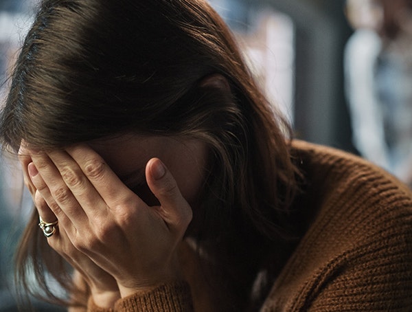 woman holding head in hands