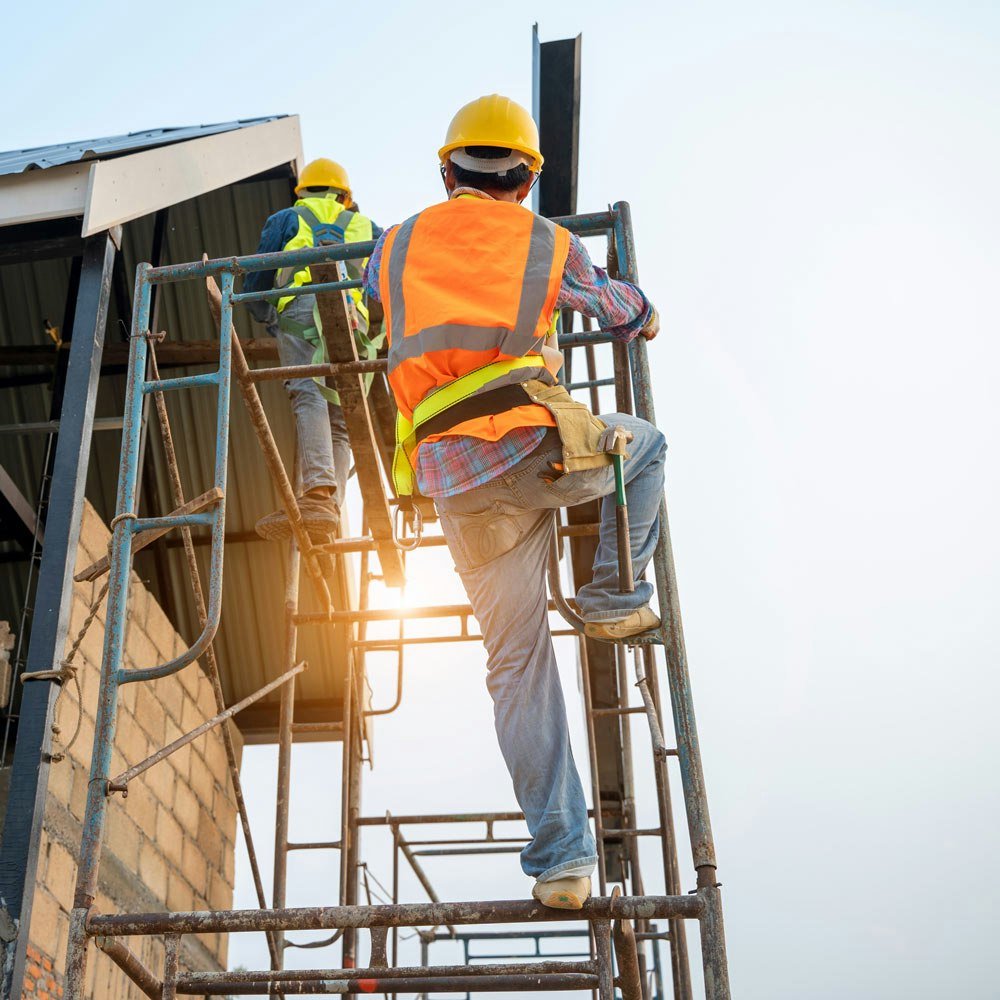 Construction workers climbing scaffolding to get on a roof