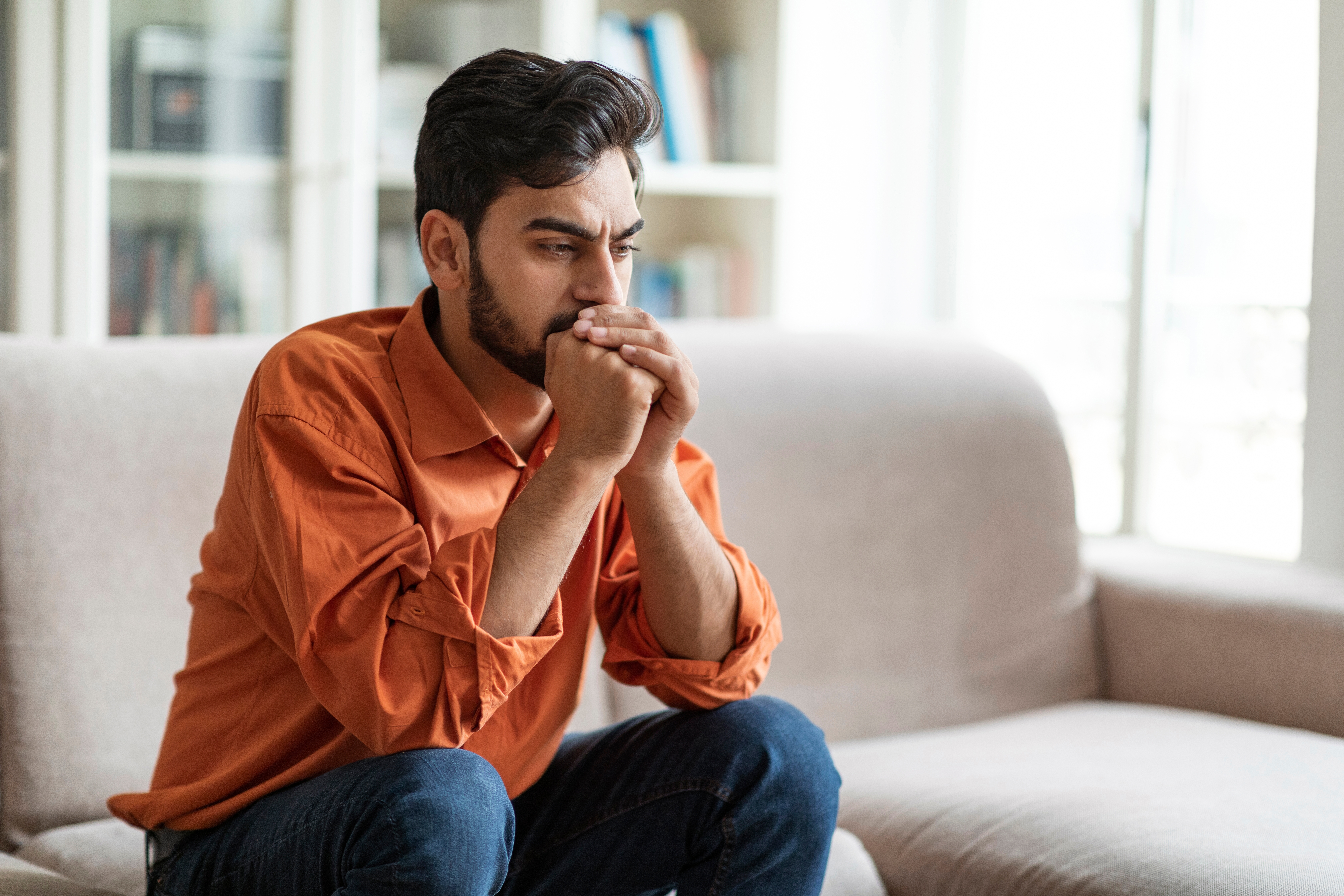 Man sitting in his living room looking stressed