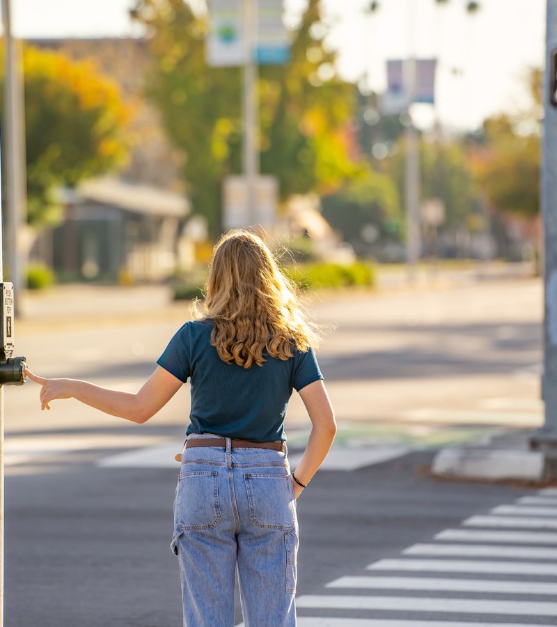Pedestrian hitting cross button at a crosswalk