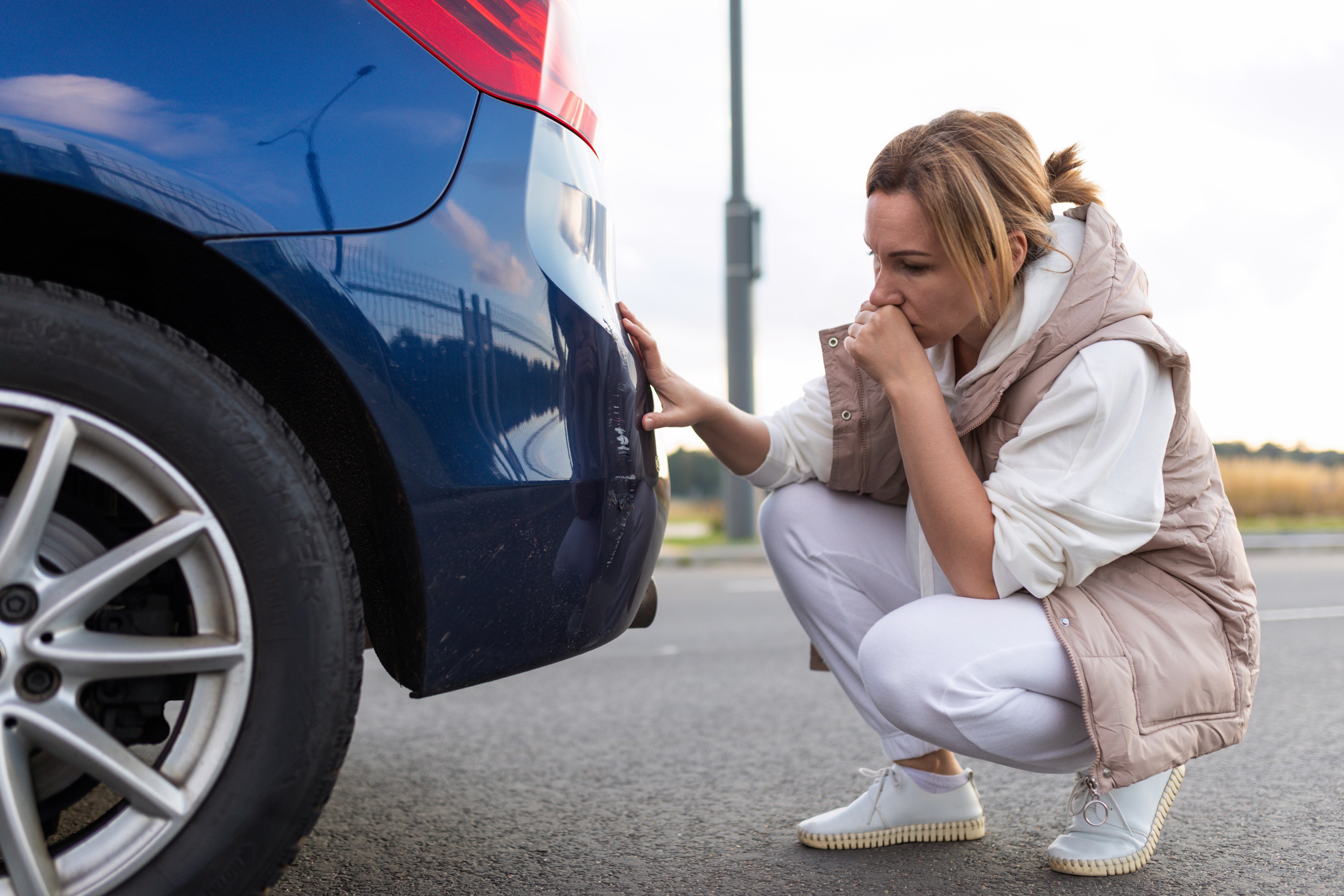 Woman looking at a scratch on her car