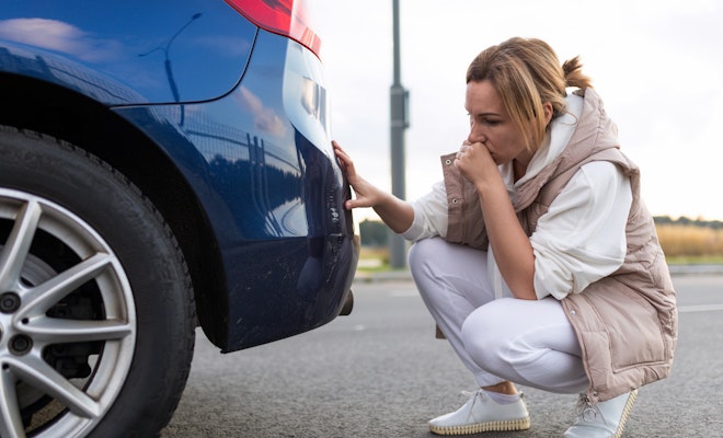 Woman looking at a scratch on her car