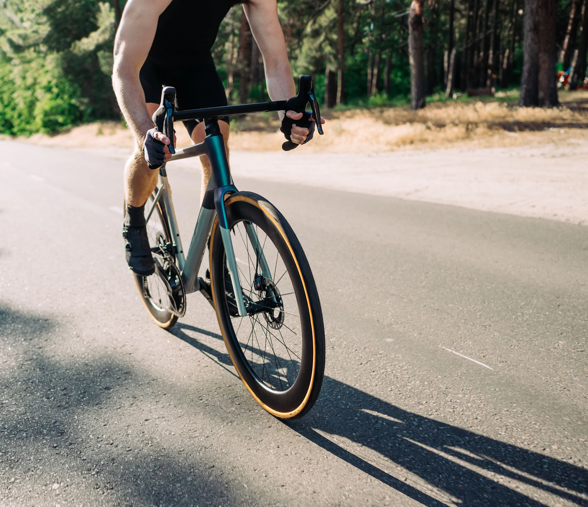 Cyclist in riding gear walking a road bike along a paved path